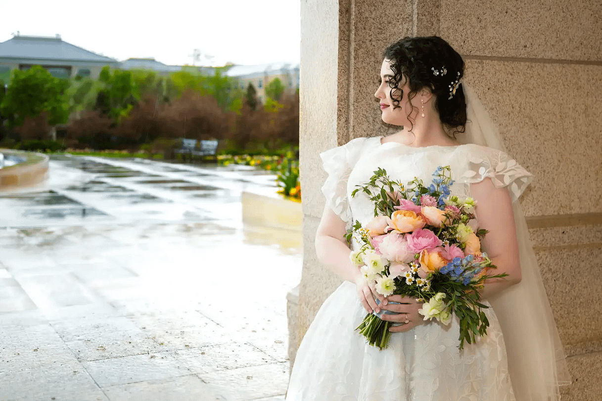 Bride in a cowboy hat adorned with jewels dancing with groom at indoor wedding reception