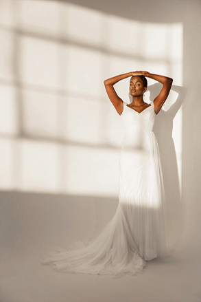 Candid portrait of smiling bride in a long sleeve gown with natural light and strong shadows