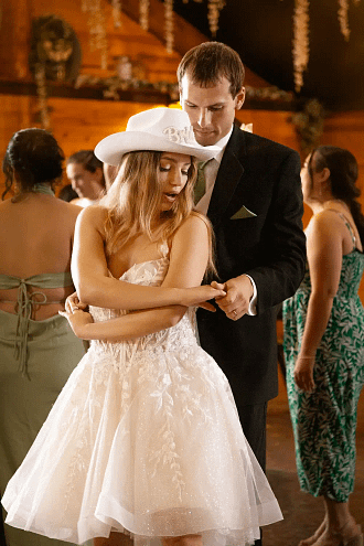 Bride wearing a party hat embracing groom outdoors during a fun wedding celebration