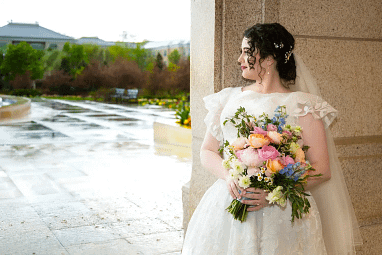 wedding bridal 2660 Bride in a lace ballgown holding a vibrant wedding bouquet outdoors