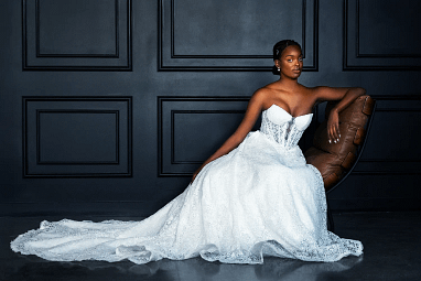 Full length portrait of a bride in a strapless gown sitting on a vintage armchair