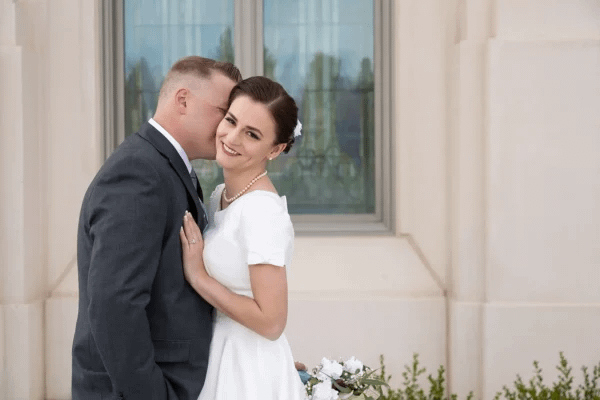 Groom embracing bride in classic outdoor wedding portrait setting